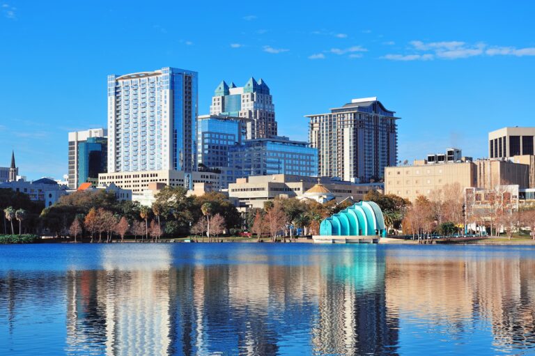 "Morning view of downtown Orlando with reflections on a calm lake."